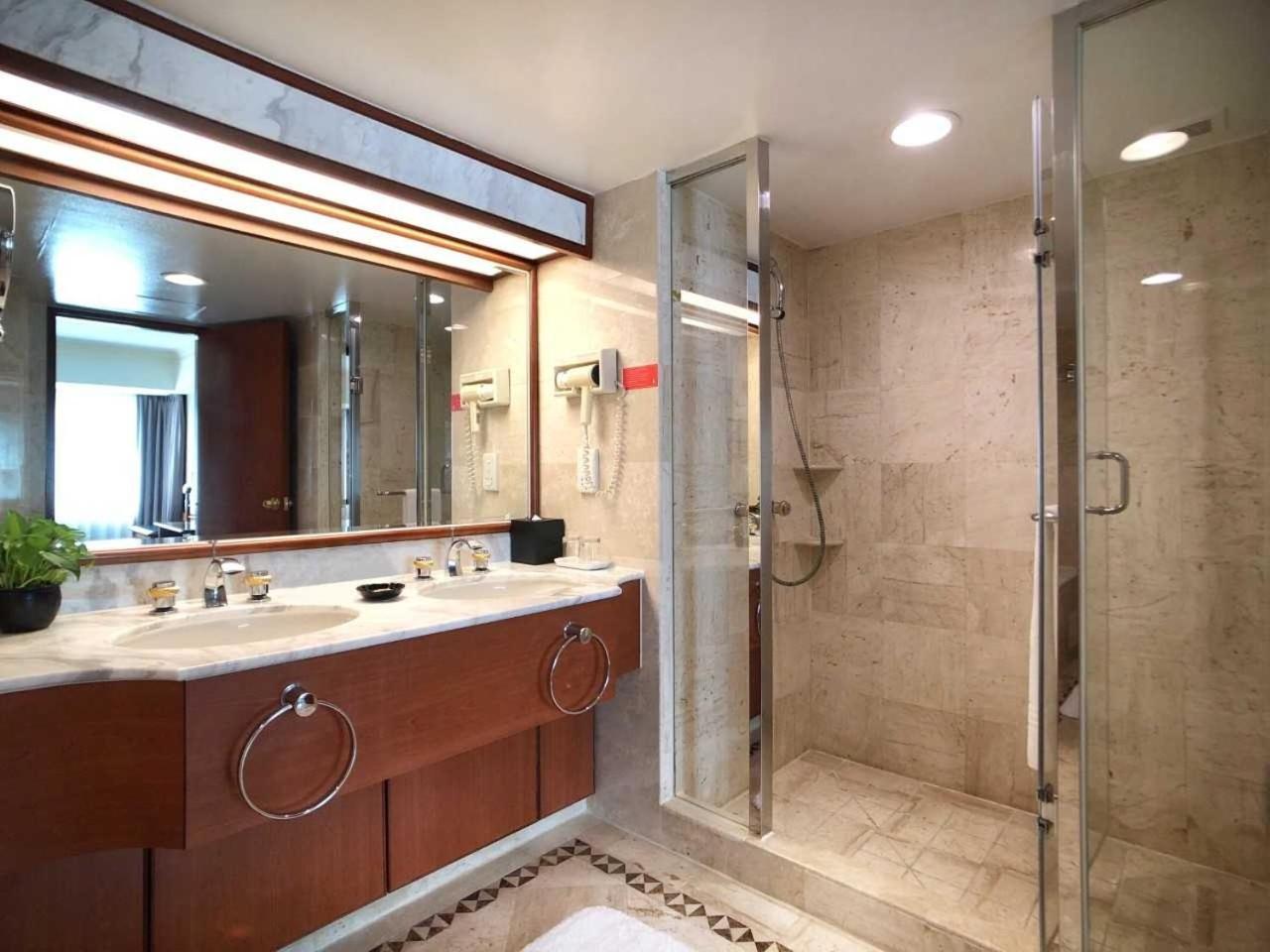 Evergreen Laurel Hotel - Тайджун Екстериор снимка The photo depicts a modern bathroom featuring a double vanity sink with a marble countertop and wooden cabinetry. Above the sinks, there is a large mirror with integrated lighting. To one side, there is a shower enclosed in glass, showcasing a sleek 