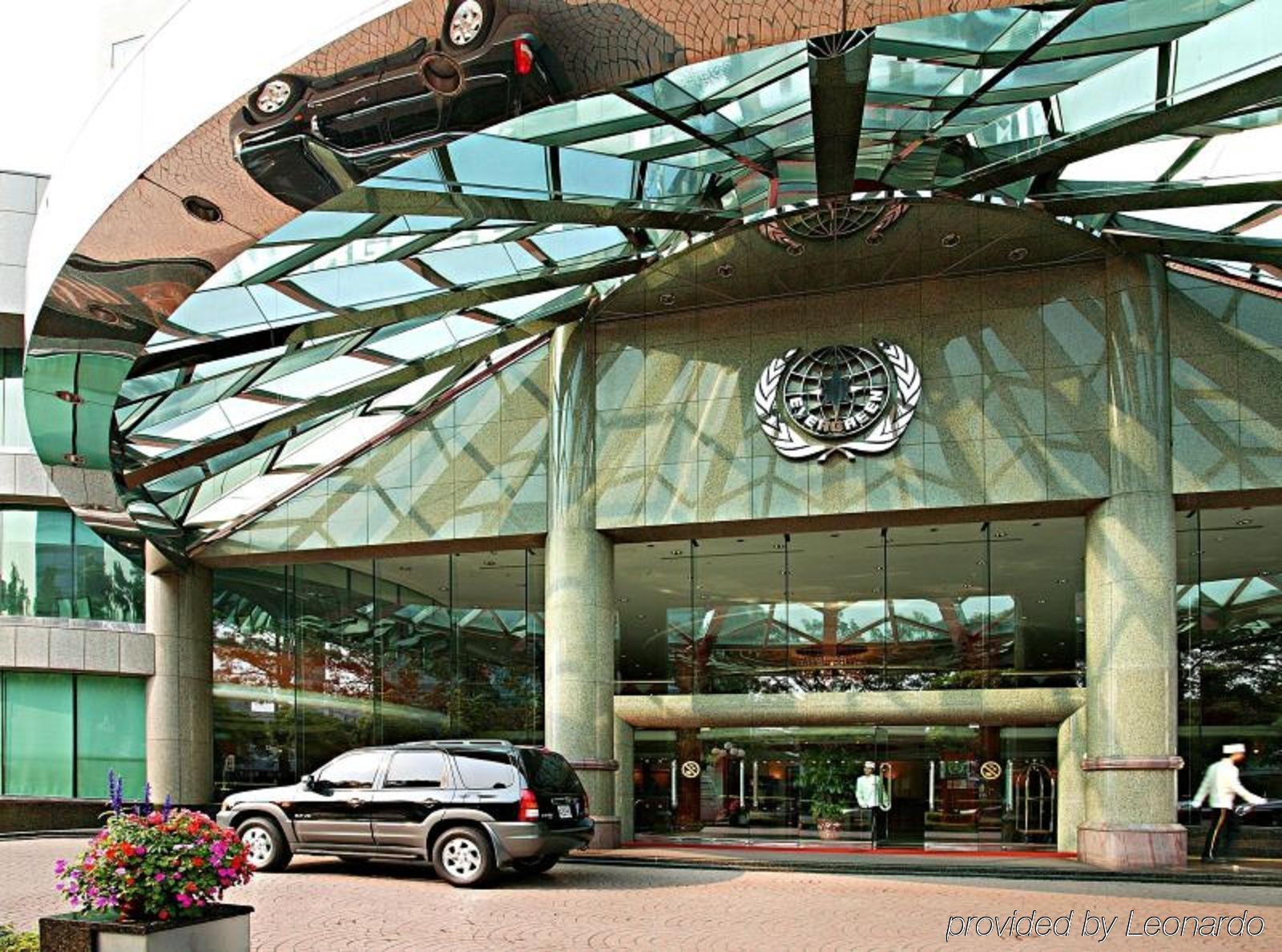 Evergreen Laurel Hotel - Тайджун Екстериор снимка The photo shows the entrance of a modern building characterized by its glass and metal architecture. The structure features a large, domed roof that reflects light, with a distinctive emblem or logo displayed prominently at the center. In front of th