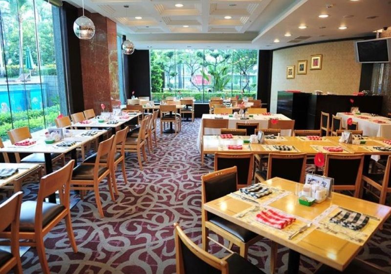 Evergreen Laurel Hotel - Тайджун Екстериор снимка The photo shows an interior of a restaurant with a spacious layout. There are several wooden tables, each set with napkins and utensils. The floor has a decorative carpet, and large windows provide a view of greenery outside. The lighting is bright, 