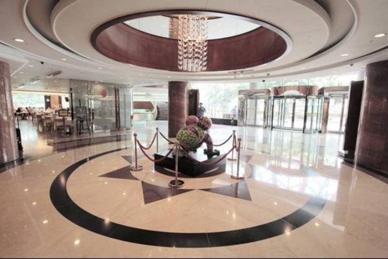 Evergreen Laurel Hotel - Тайджун Екстериор снимка The photo depicts an elegant indoor space, likely the lobby of a hotel or a building. The flooring is made of polished marble tiles, featuring a circular design with contrasting black and light-colored sections. At the center, there is a sculpture su
