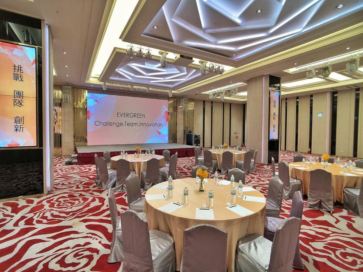 Evergreen Laurel Hotel - Тайджун Екстериор снимка The photo shows a conference or event space set up for a gathering. The room features several round tables with light-colored tablecloths and chairs, each with decoration, possibly for dining or discussion. A large screen displays the text "EVERGREEN