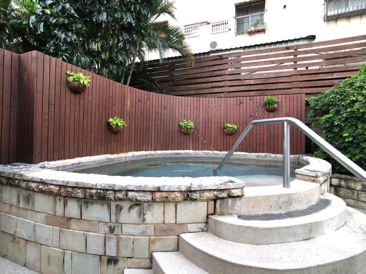 Evergreen Laurel Hotel - Тайджун Екстериор снимка The photo shows a small outdoor hot tub or spa area. It's surrounded by a wooden fence, with several planters containing greenery attached to the wall. The hot tub is round, with a stone border, and there are steps leading up to it with a stainless s